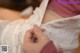 A woman is sewing a wedding dress on a table.