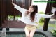 A woman in a white shirt and yellow panties posing by a pool.
