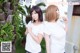 A couple of women standing next to each other near a palm tree.