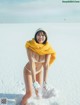 A woman in a white bikini standing in the snow.