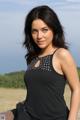 A woman in a black tank top sitting on a rock.