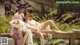 A couple of women sitting on top of a stone bench.