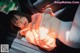 A woman in an orange sweatshirt is sitting in a car.