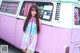 A woman standing in front of a pink and white van.