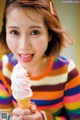 A woman holding an ice cream cone in her hand.