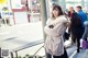 A woman in a fur coat is standing on the sidewalk.